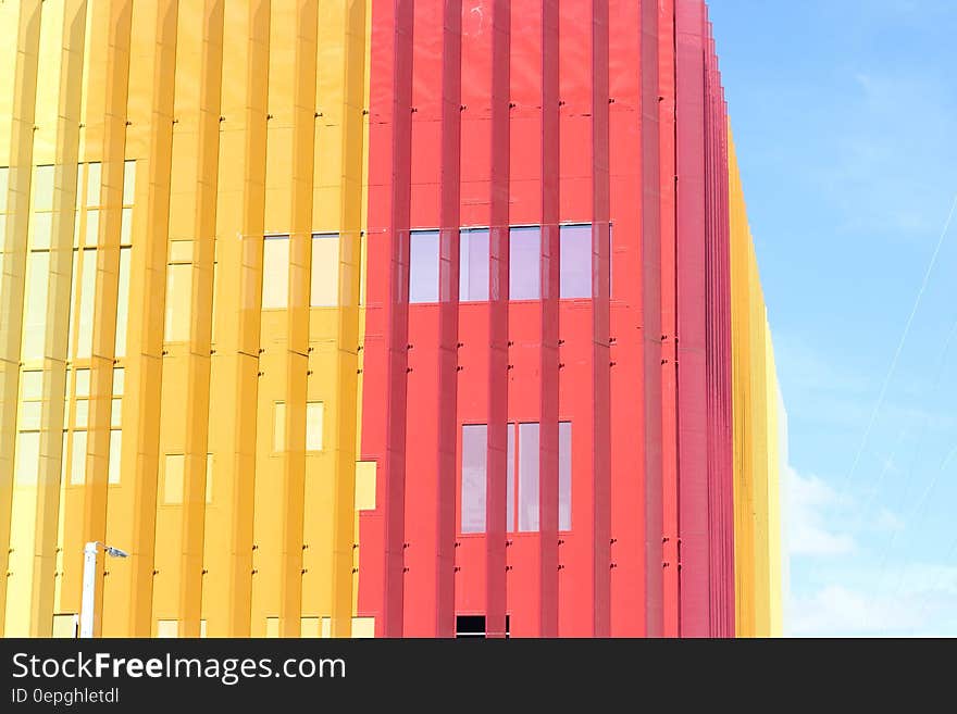 Multistory building of contemporary architectural design with steel construction, in pink and yellow colors, pale blue sky. Multistory building of contemporary architectural design with steel construction, in pink and yellow colors, pale blue sky.