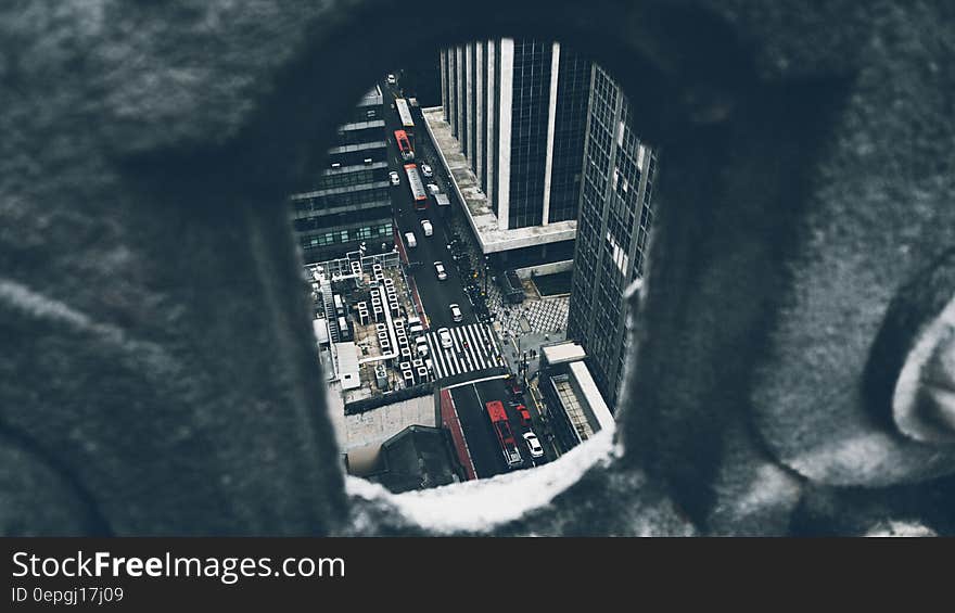 Aerial view of busy traffic on city streets viewed through gap in wall.