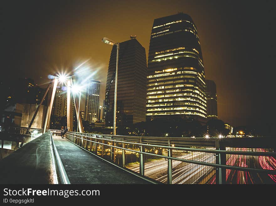 A night view of a city with traffic passing under a bridge. A night view of a city with traffic passing under a bridge.