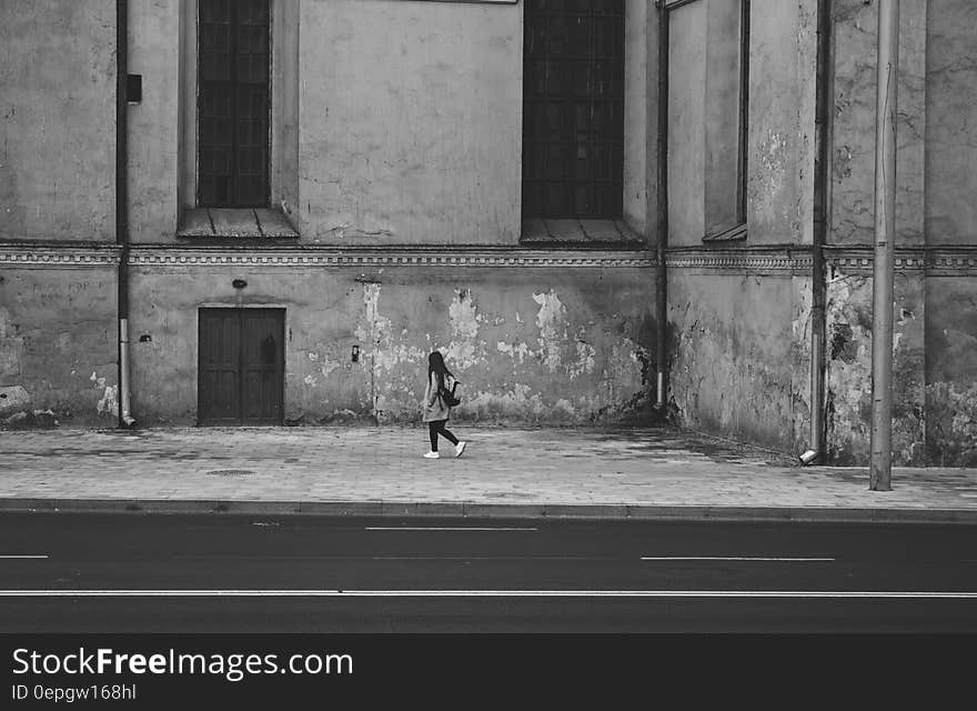 Gray Scale Photography of Woman Walking Near High Rise Building