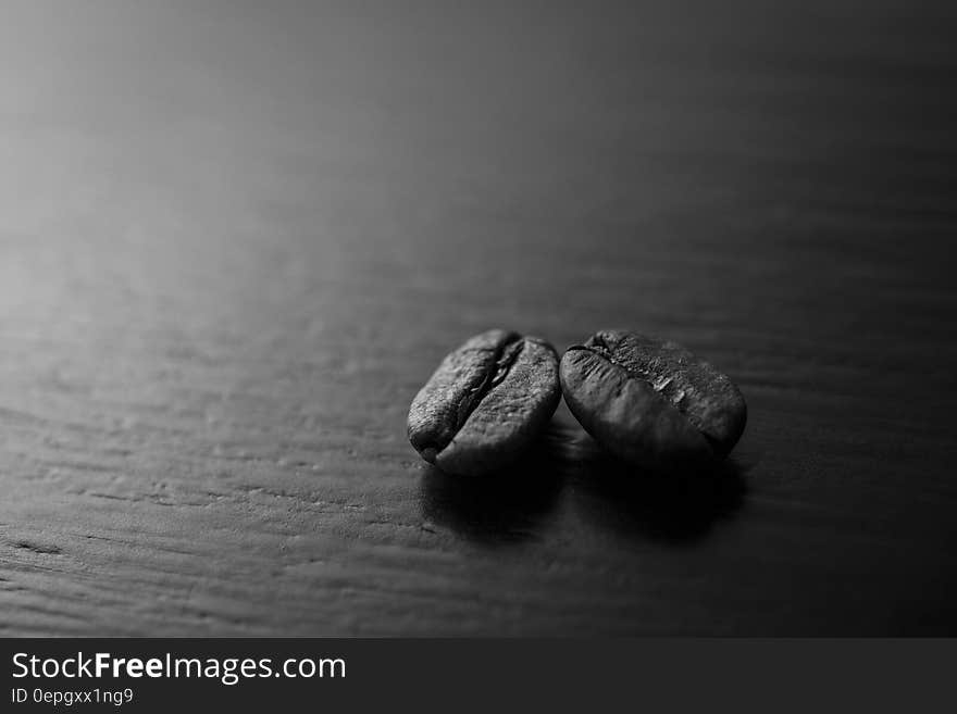 Close up of roasted whole coffee beans on wood in black and white. Close up of roasted whole coffee beans on wood in black and white.