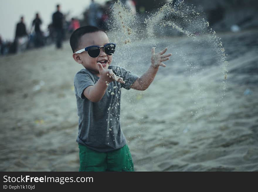 Kid throwing sand in air while playing at beach. Kid throwing sand in air while playing at beach.