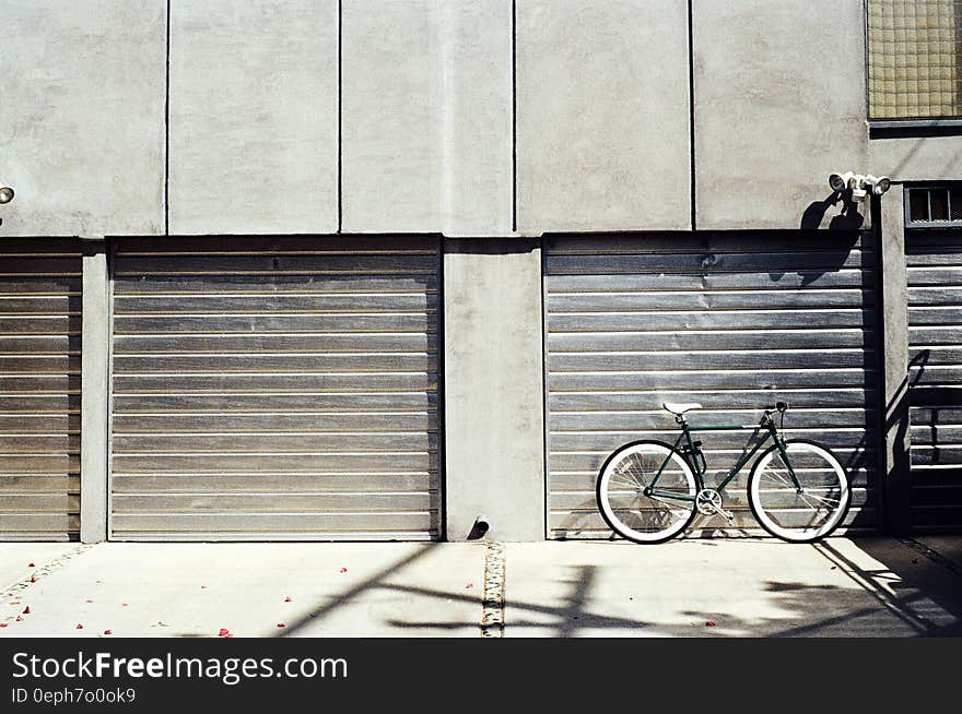 Bicycle leaning against garage door on sunny day. Bicycle leaning against garage door on sunny day.