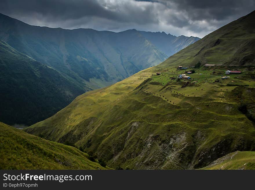 Village on hillside of green mountain with cloudy skies. Village on hillside of green mountain with cloudy skies.