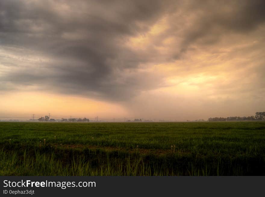 Sunset in stormy skies over rural meadow.