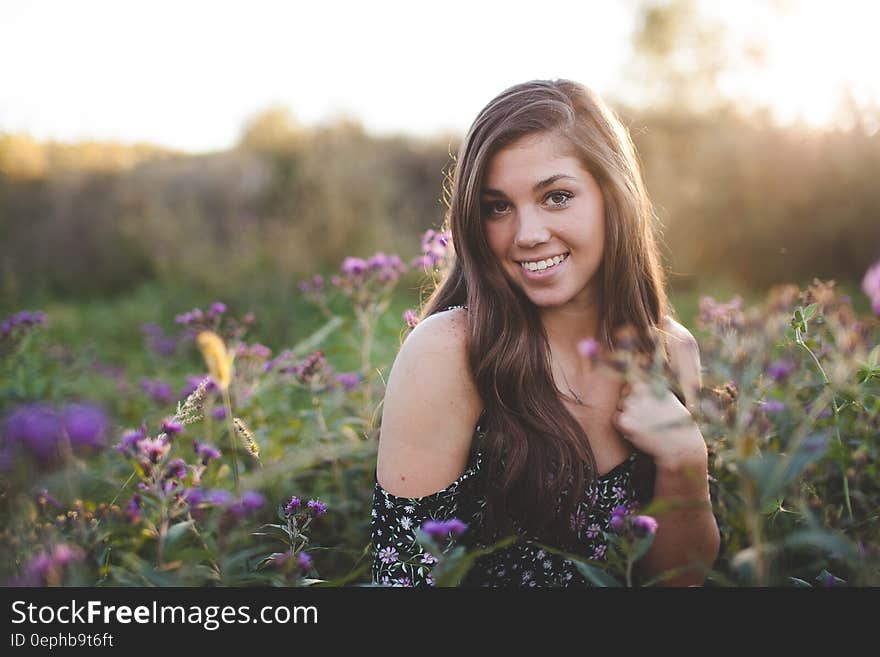 Woman in Black Off Shoulder Dress Standing in Green Flower Field during Daytime