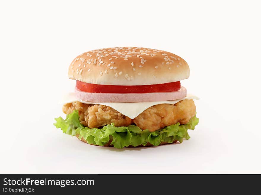 Giant hamburger in seeded bun with cheese, ham, tomato and crispy green lettuce, white background. Giant hamburger in seeded bun with cheese, ham, tomato and crispy green lettuce, white background.