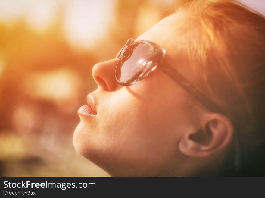 Closeup portrait of girl with red hair and wearing spectacles looking up as if in prayer and bathed in a golden glow. Closeup portrait of girl with red hair and wearing spectacles looking up as if in prayer and bathed in a golden glow.