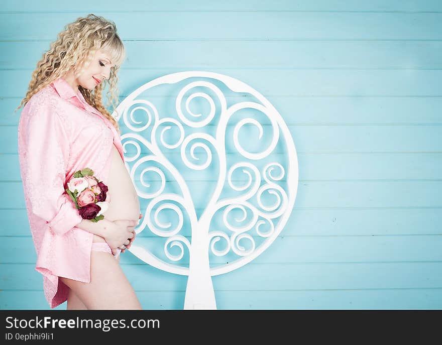 A pregnant woman holding her belly with a blue background.