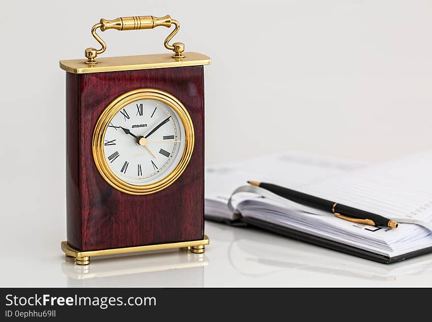 Vintage clock on tabletop with open appointment book and pen. Vintage clock on tabletop with open appointment book and pen.