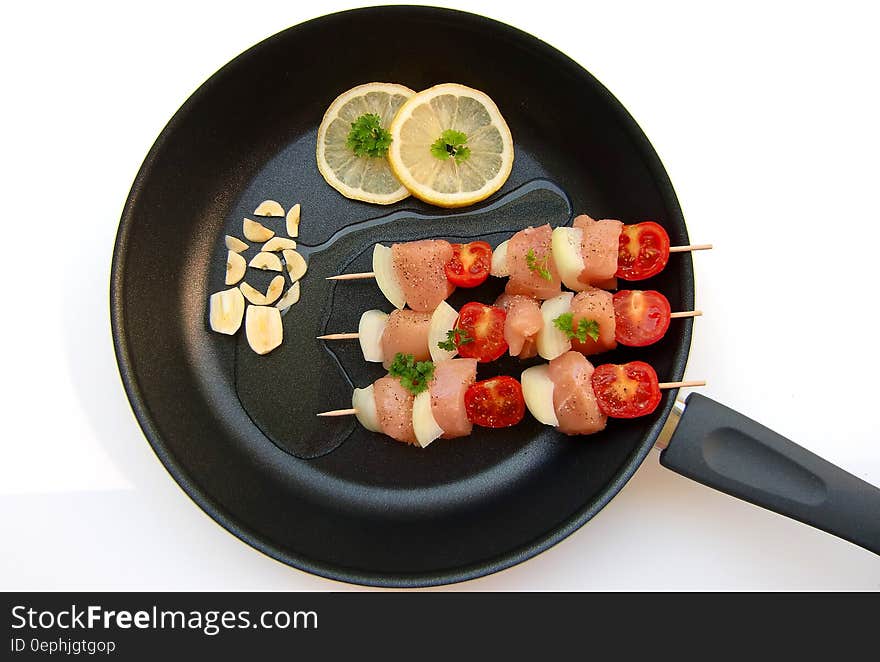 Barbecue Stick Beside Lemon on Black Frying Fan