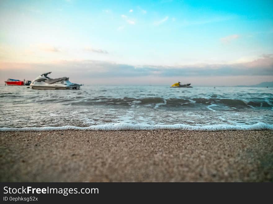 Jet skis in waves offshore of sandy beach on sunny day. Jet skis in waves offshore of sandy beach on sunny day.