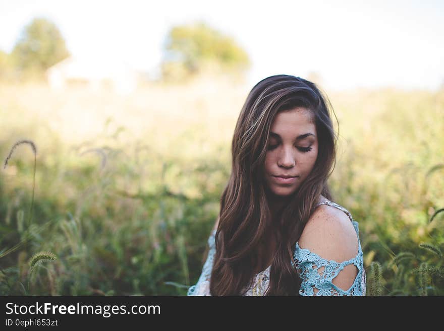 Woman Wearing Teal Off Shoulder While Seating on Grass Photo