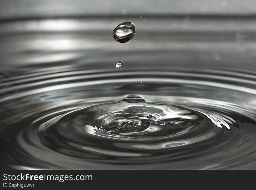 Water drop creating ripples across surface in black and white. Water drop creating ripples across surface in black and white.