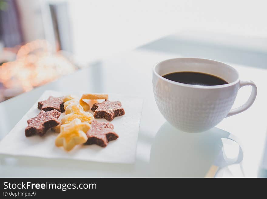 White Tea Cup Beside White Square Saucer With Star Shaped Cookies