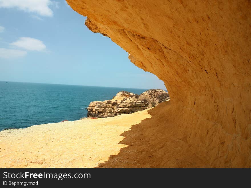 Empty sand beach with rocky ledge on sunny day. Empty sand beach with rocky ledge on sunny day.