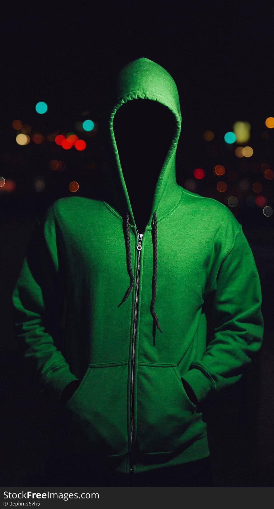 Faceless person standing in city outdoor at night wearing green hoodie jacket. Faceless person standing in city outdoor at night wearing green hoodie jacket.