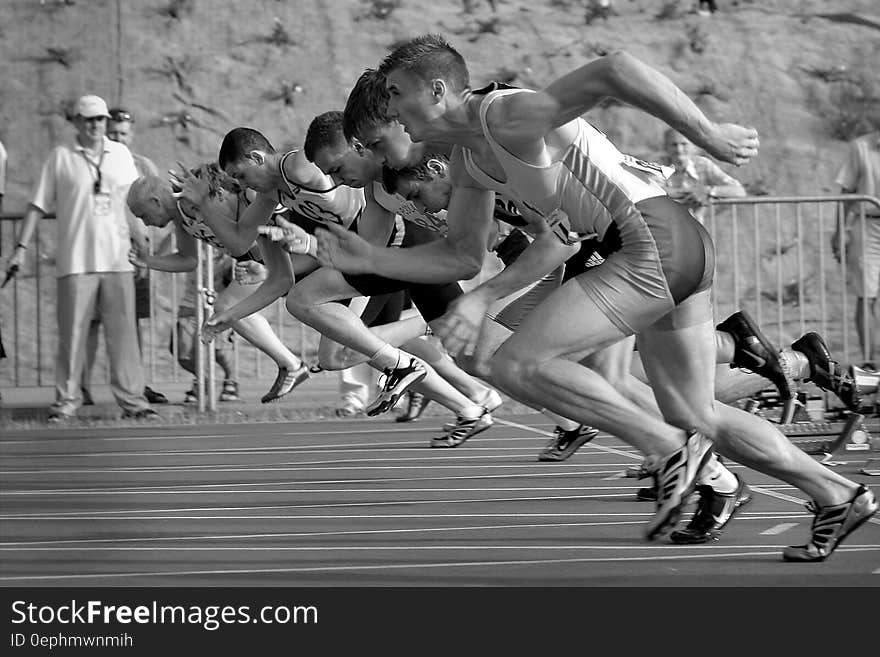 Athletes Running on Track and Field Oval in Grayscale Photography