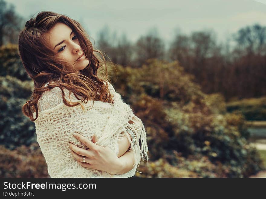 Portrait of woman wrapped in white shawl standing outdoors with serious expression. Portrait of woman wrapped in white shawl standing outdoors with serious expression.