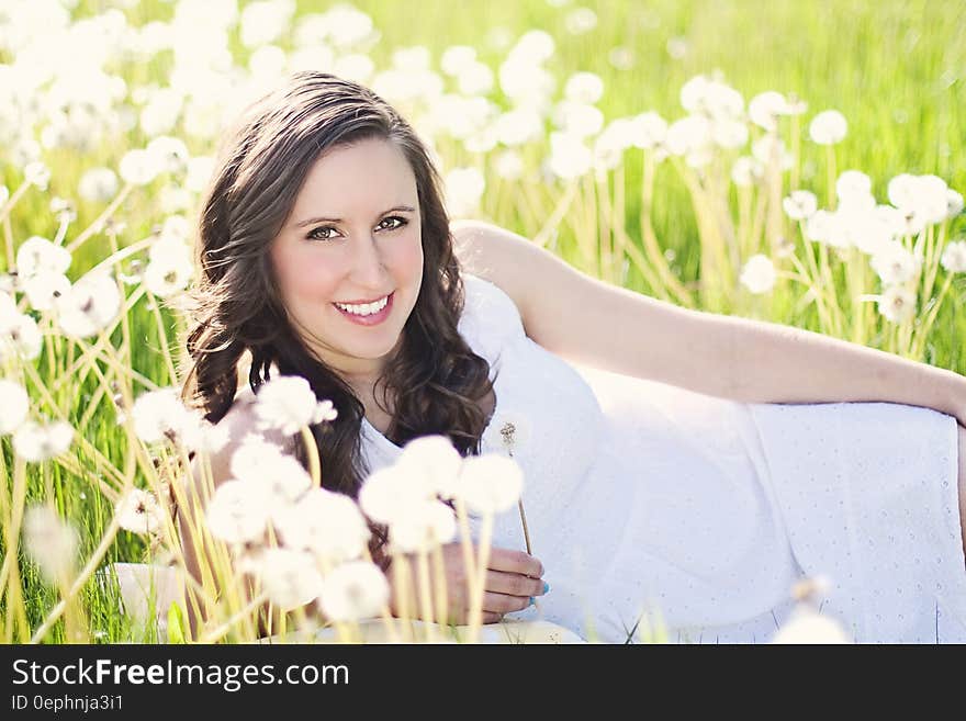 Woman in White Sleeveless Dress Lying on Green Grass Field