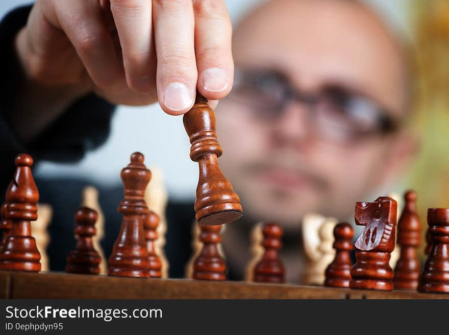 Close up of man's hand moving wooden chess pieces on board. Close up of man's hand moving wooden chess pieces on board.