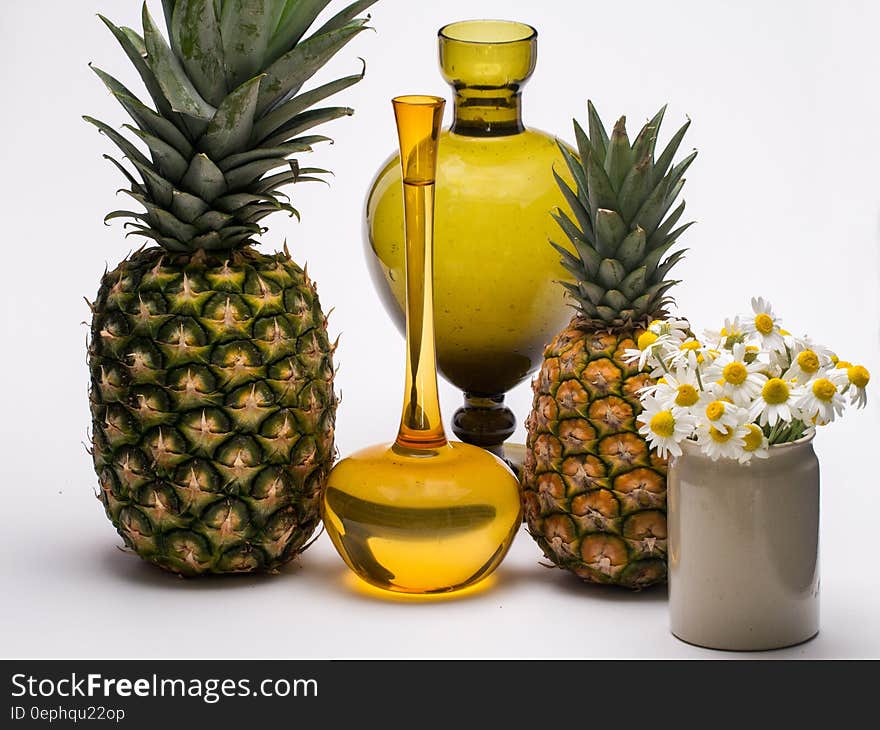 Still life with fresh whole pineapples, gold vases and cut white daisy flowers in crock. Still life with fresh whole pineapples, gold vases and cut white daisy flowers in crock.