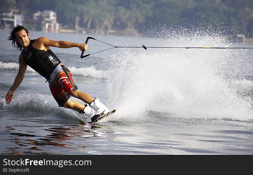 Man in Black Tank Top and Red Shorts Waveboarding