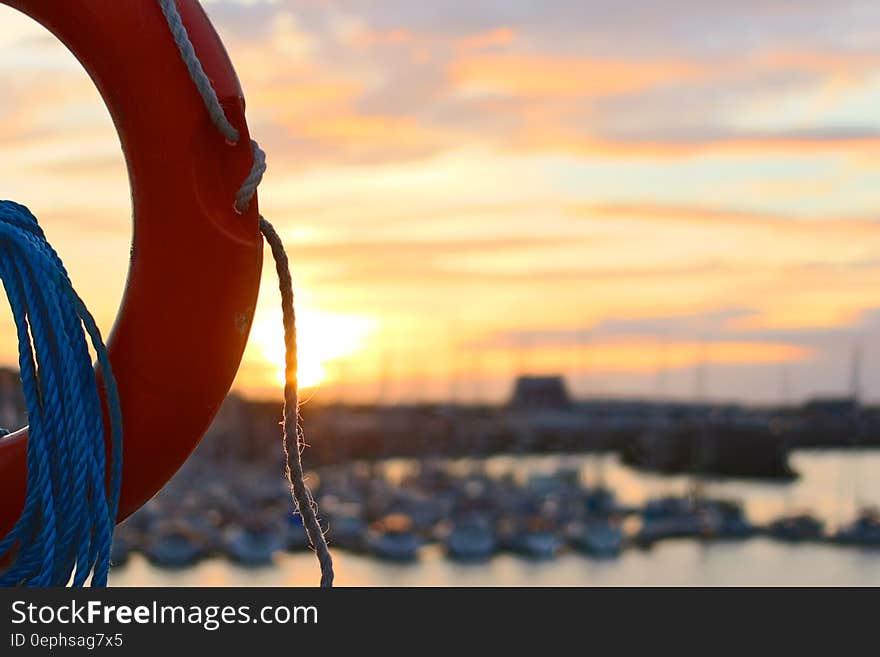 Close up of life ring next to boats in harbor at sunset. Close up of life ring next to boats in harbor at sunset.