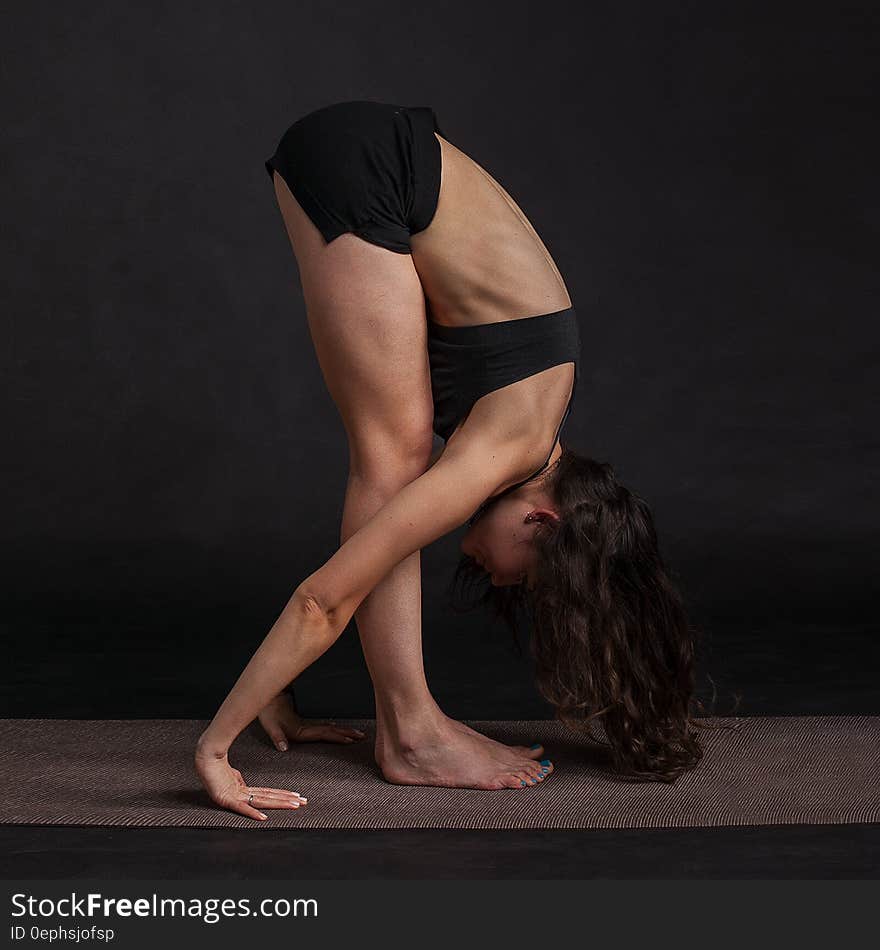 Studio portrait of young woman in black exercise attire stretching while standing. Studio portrait of young woman in black exercise attire stretching while standing.