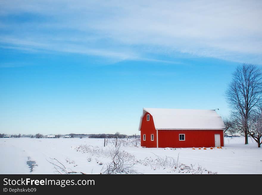 Red Barn House in the Middle of Snow Field During Daytime