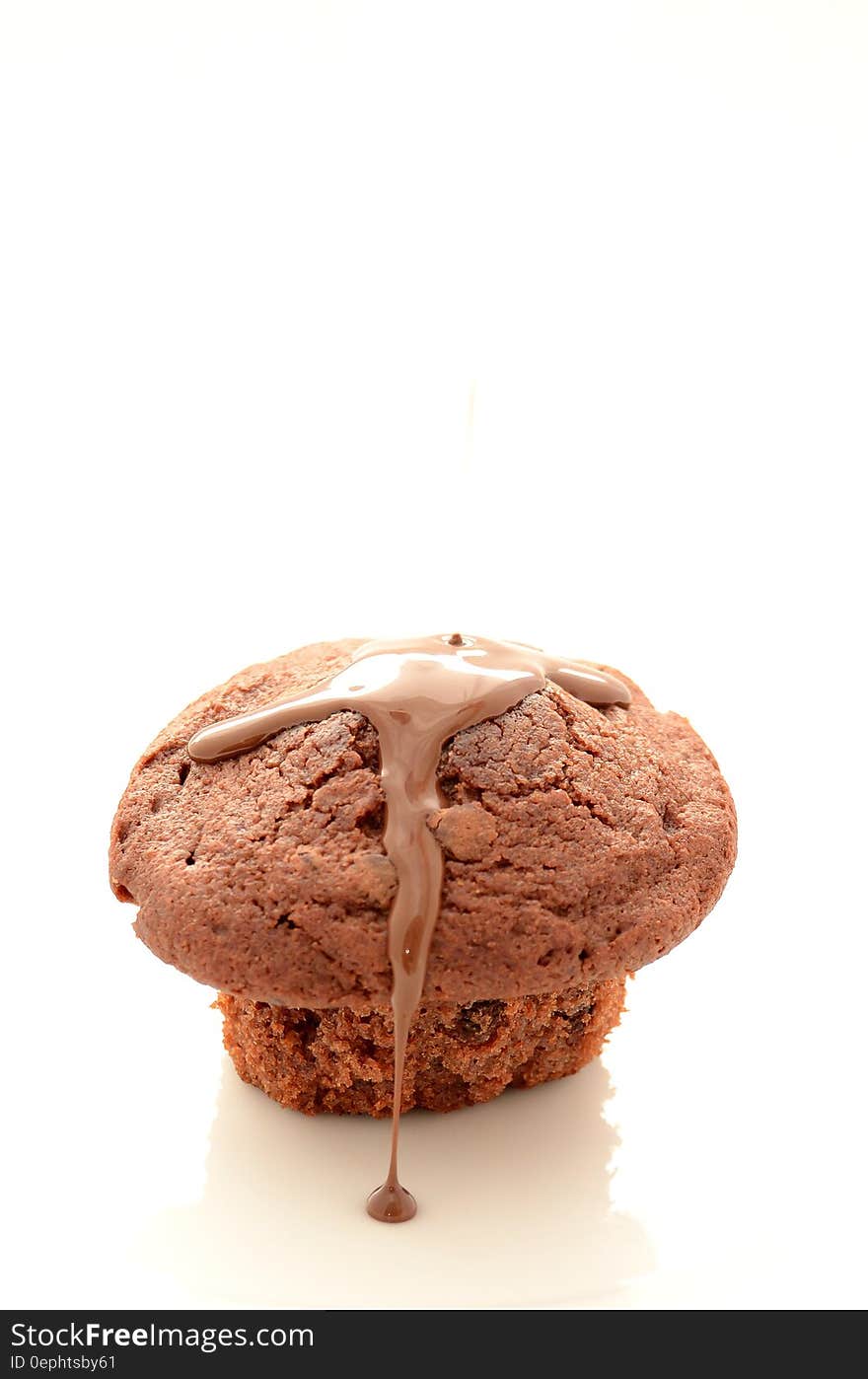 Brown muffin with currants and runny chocolate sauce, white background. Brown muffin with currants and runny chocolate sauce, white background.