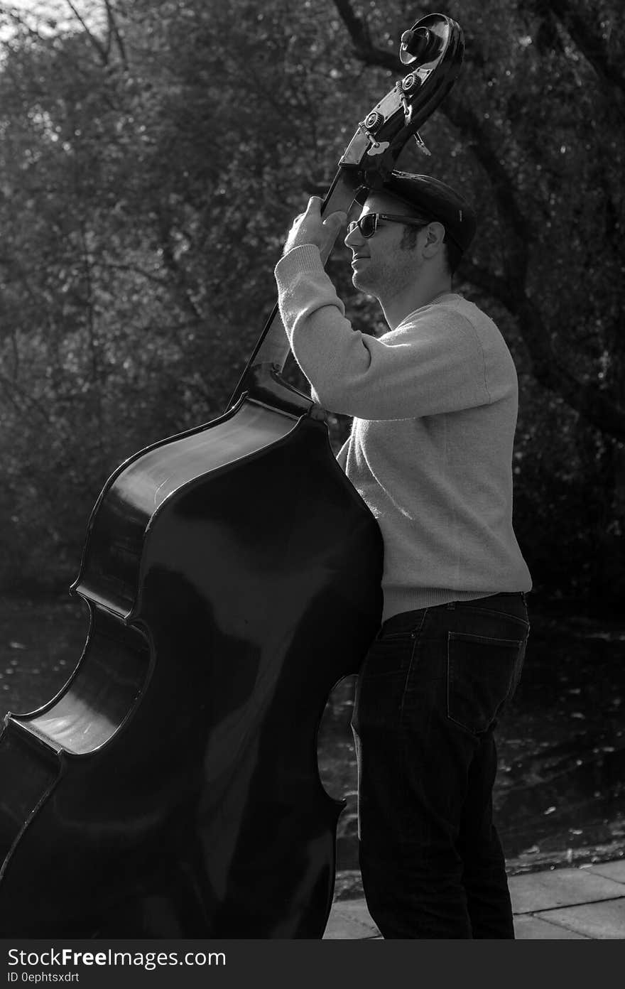 Musician playing bass outdoors in black and white.