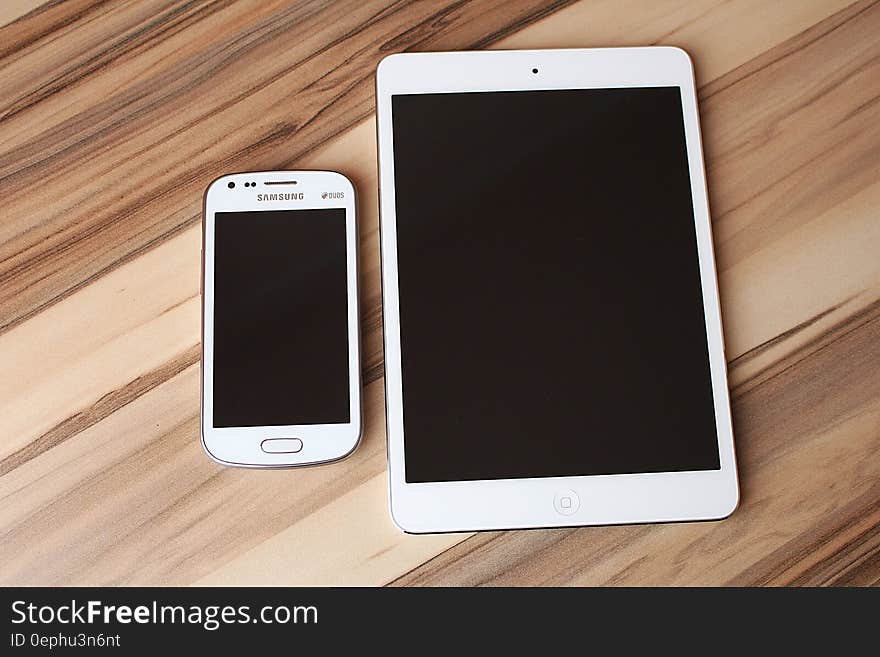 Blank touchscreen on Samsung smartphone and tablet on wooden desk. Blank touchscreen on Samsung smartphone and tablet on wooden desk.