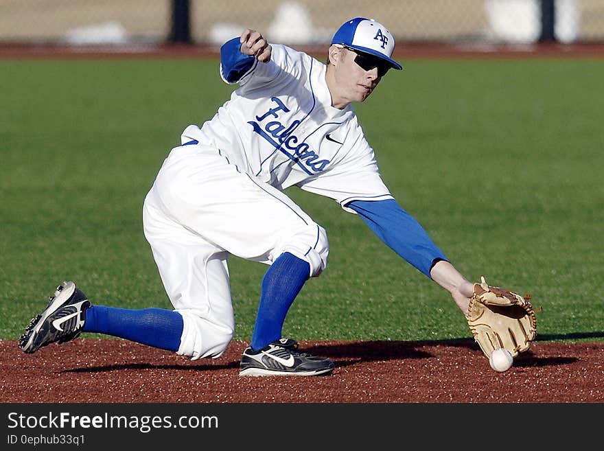 Man Wearing Blue and White Falcons Baseball Jersey Shirt With Brown Baseball Gloves Catching White Baseball