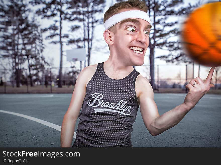 Person in Grey Tank Top Spinning Ball on Forefinger