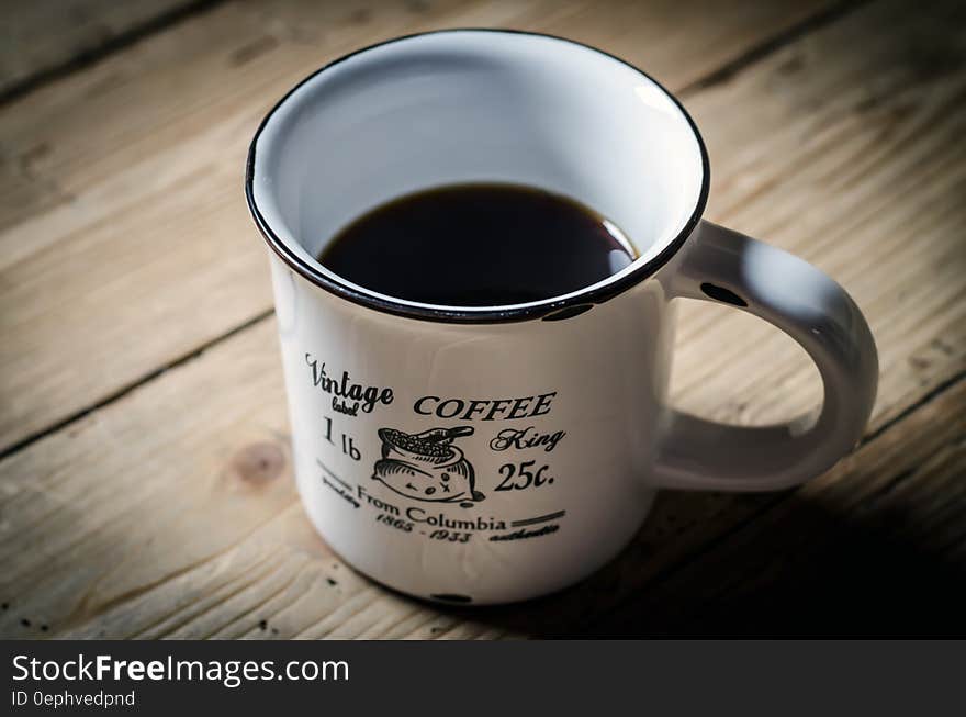 Elevated view of cup black coffee in vintage cup on rustic wooden table. Elevated view of cup black coffee in vintage cup on rustic wooden table.