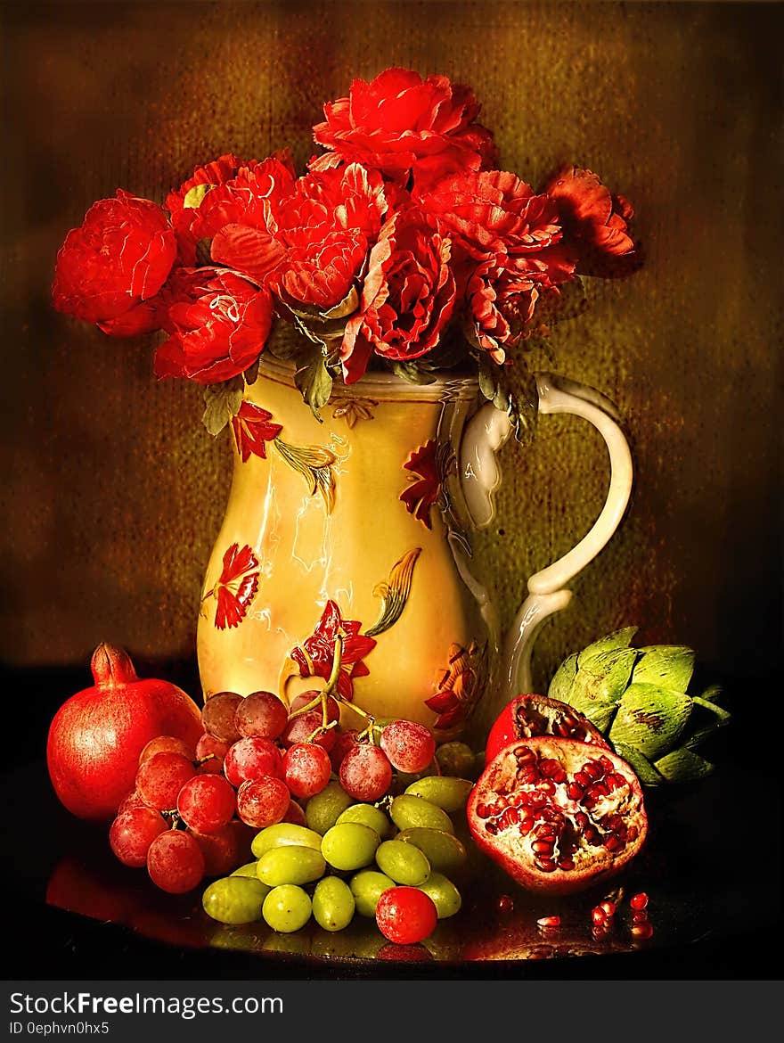 Red Petaled Flowers in White Red Floral Ceramic Vase Beside Red and Green Grapes