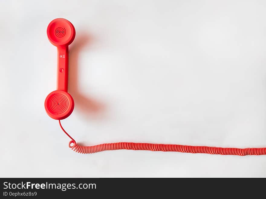 Red telephone receiver and cable on white background with copy space.