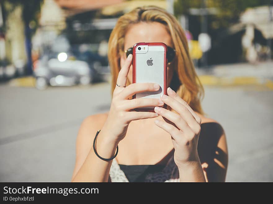 Woman on streets using iPhone camera on sunny day. Woman on streets using iPhone camera on sunny day.