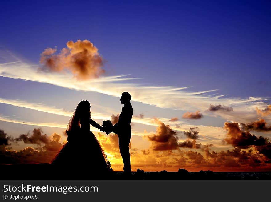 Silhouette of Wedding Couple Holding Hands Under Cloudy Blue Sky