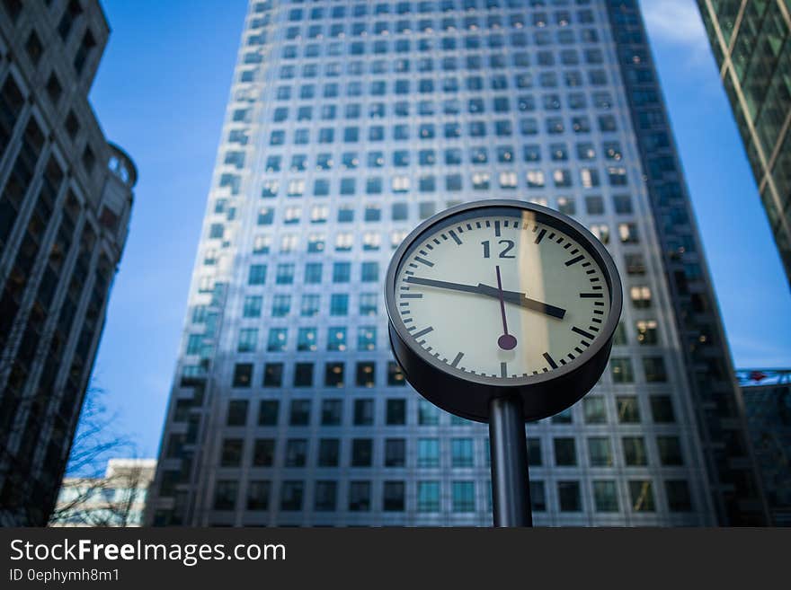 Black and Gray Round Analog Watch at 3:47 Across High Rise Building