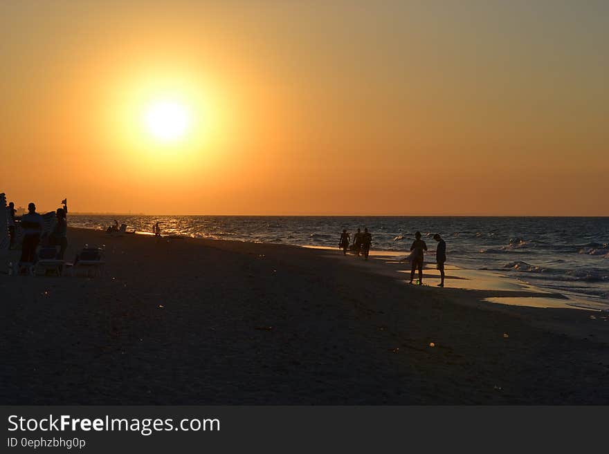 Sun setting over silhouettes of people on beach. Sun setting over silhouettes of people on beach.