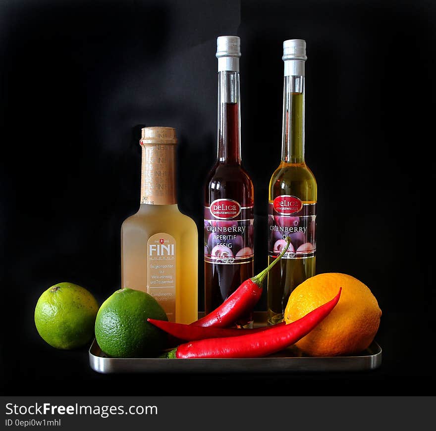 A tray with cranberry oil, white vinegar, limes and chili peppers. A tray with cranberry oil, white vinegar, limes and chili peppers.