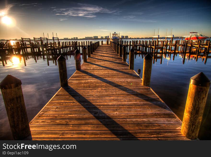 Brown Wooden Dock on Blue Water Under White Clouds and Blue Sky during Daytime