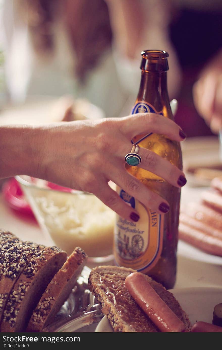 Person Holding Brown Labeled Bottle