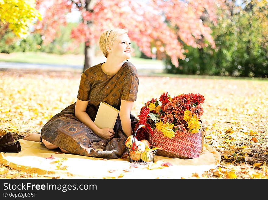 A woman with a basket of flowers in a park in the autumn. A woman with a basket of flowers in a park in the autumn.