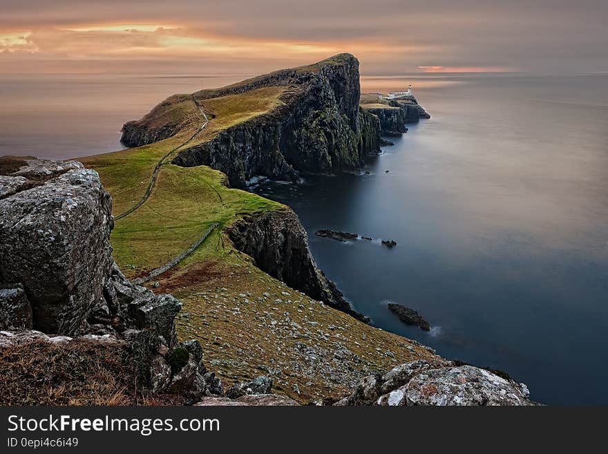 Scenic view of cliffs on the coastline of the Isle of Skye with lighthouse in the background at sunset, Scotland. Scenic view of cliffs on the coastline of the Isle of Skye with lighthouse in the background at sunset, Scotland.