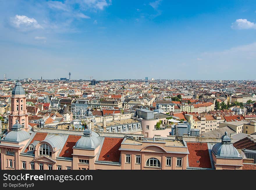 View over the rooftops in a major (possibly Italian) city with many buildings having red roof tiles and domes of religious institutions, blue sky and cloud background. View over the rooftops in a major (possibly Italian) city with many buildings having red roof tiles and domes of religious institutions, blue sky and cloud background.