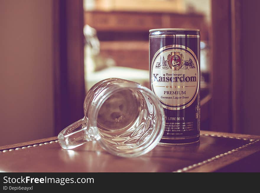 An empty laid down beer mug and a beer can beside on a wooden table. An empty laid down beer mug and a beer can beside on a wooden table.