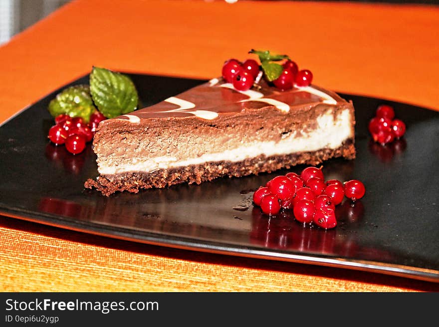 A piece of choco cheesecake with cranberry garnish.